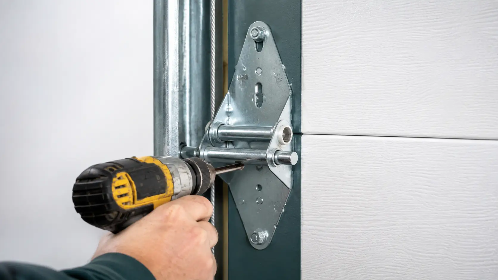 Technician checking garage door rollers hinges bearings springs cables and tracks for wear in Greenfield Indiana