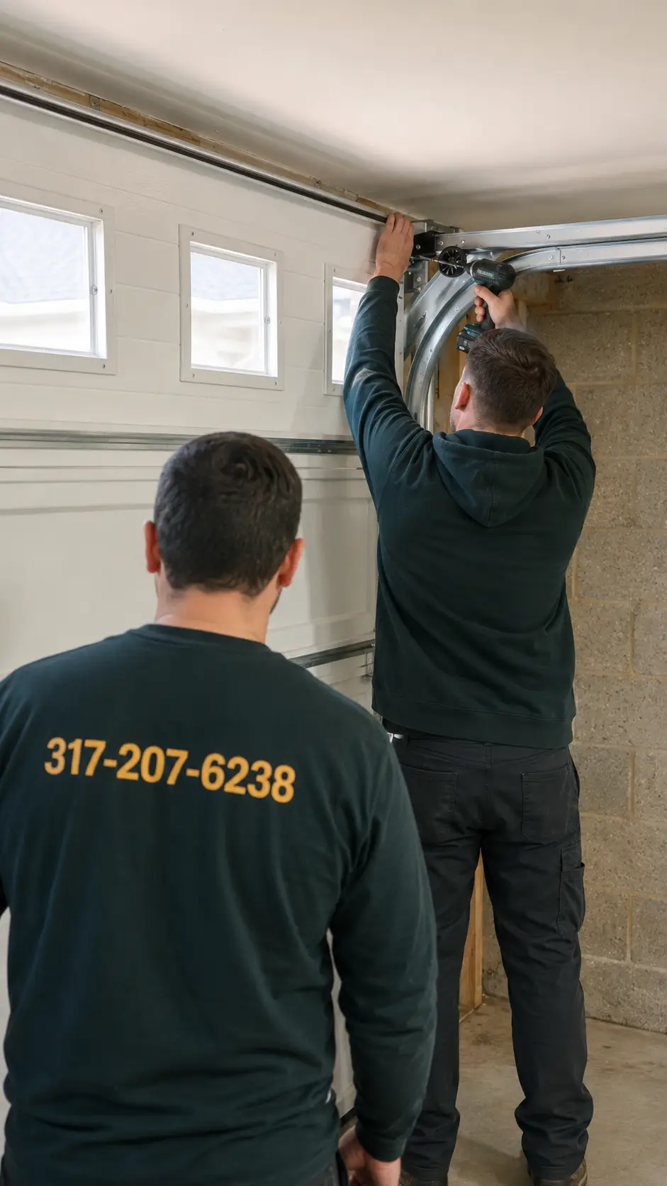 Technician inspecting garage door symptoms including track roller cable hinge and bearing problems in Greenfield Indiana